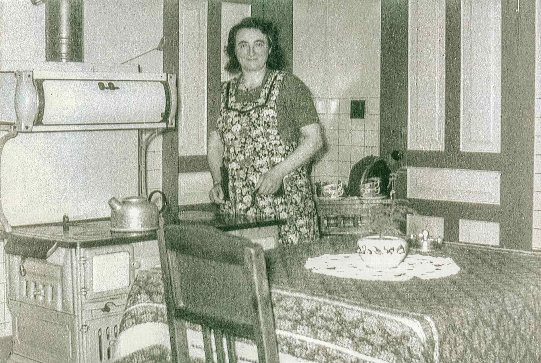 My mother in the kitchen. Notice that the stove is a wood-burning stove. Mostly Dutch furnishing.